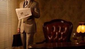 Un professionista nel suo studio che regge una valigetta mentre legge il giornale