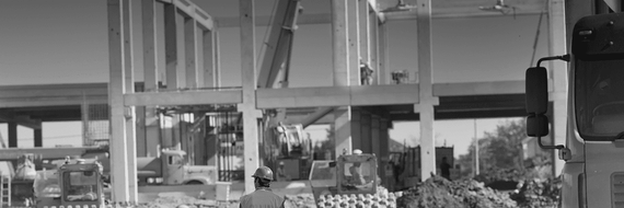 Schwarz-weiße Industrieanlage mit großen Maschinen, Rohren und dichten Materialhaufen auf dem Fabrikboden