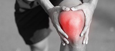a man in shorts is holding jis knee in pain.
