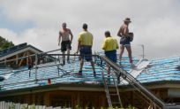 four builders working on a roof