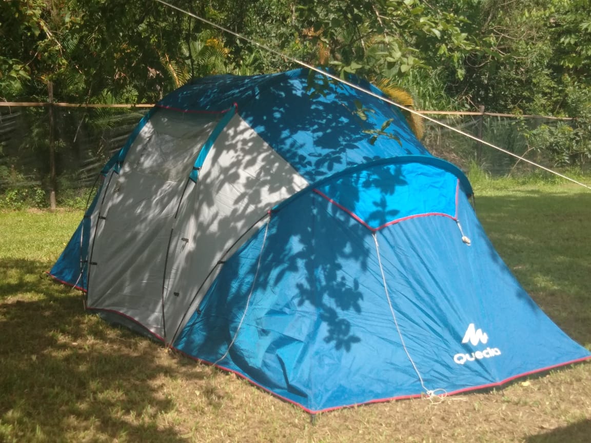 Uma tenda azul e cinza está no topo de um campo verdejante.