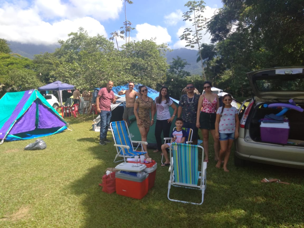 Um grupo de pessoas em frente a uma barraca e um carro