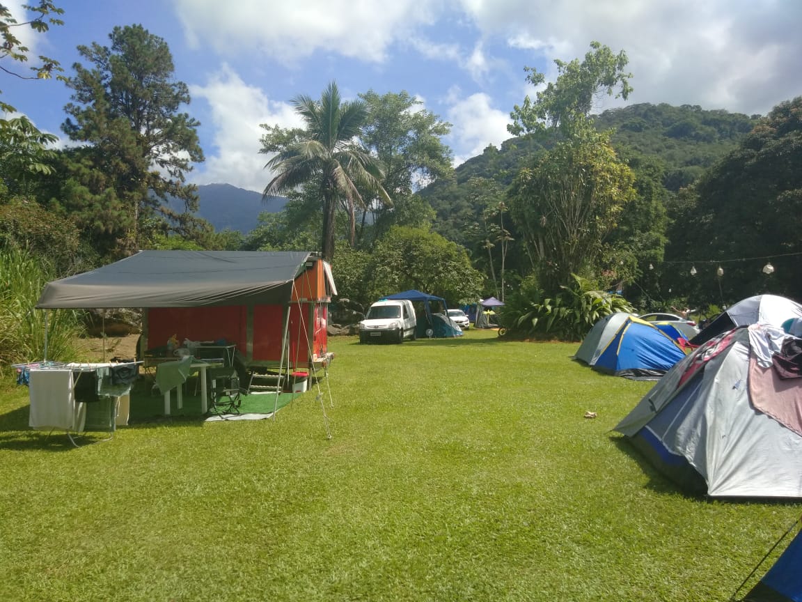 Um grupo de tendas está no topo de um campo verdejante.