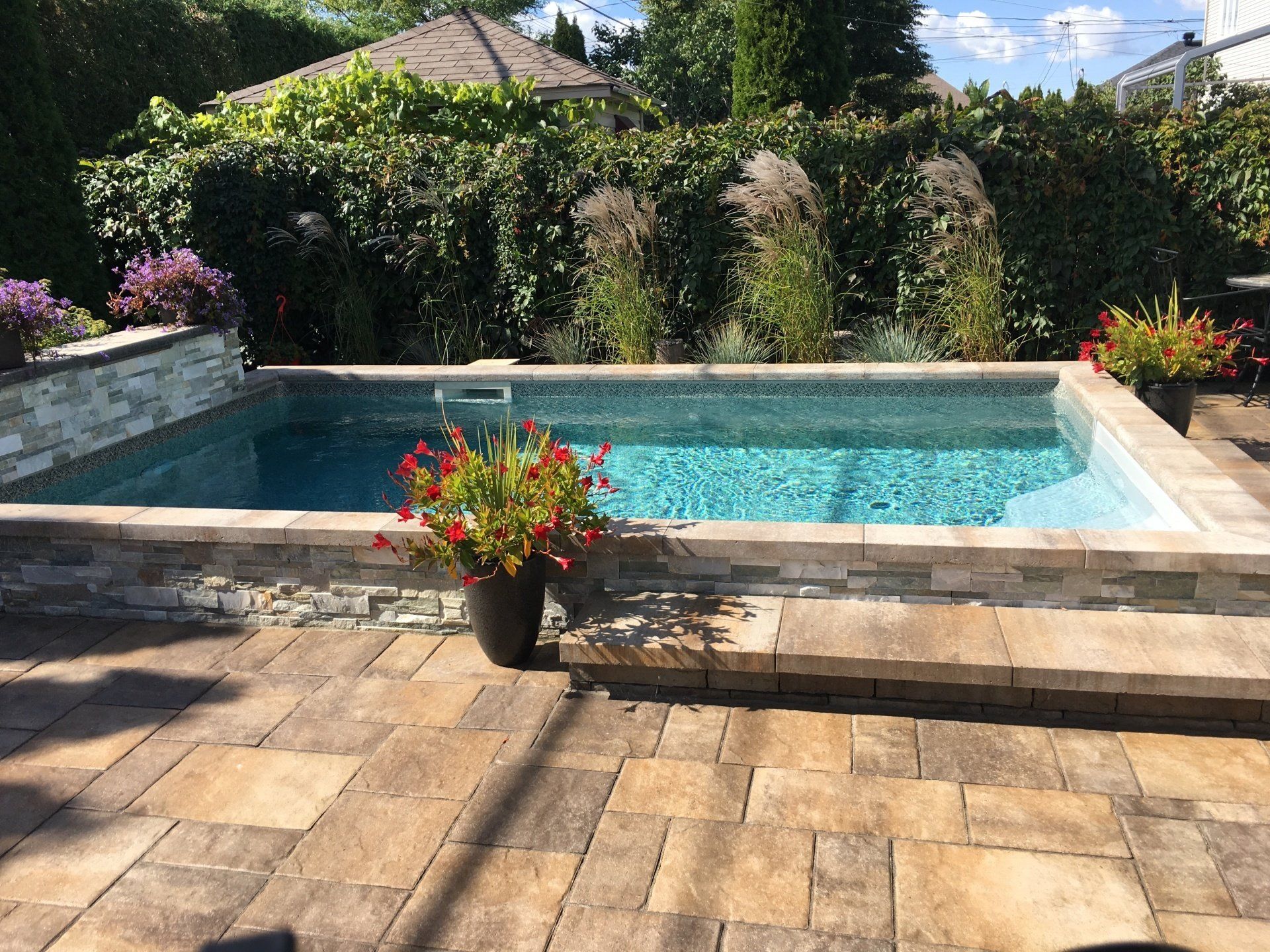 Une petite piscine avec des fleurs dans un pot devant.