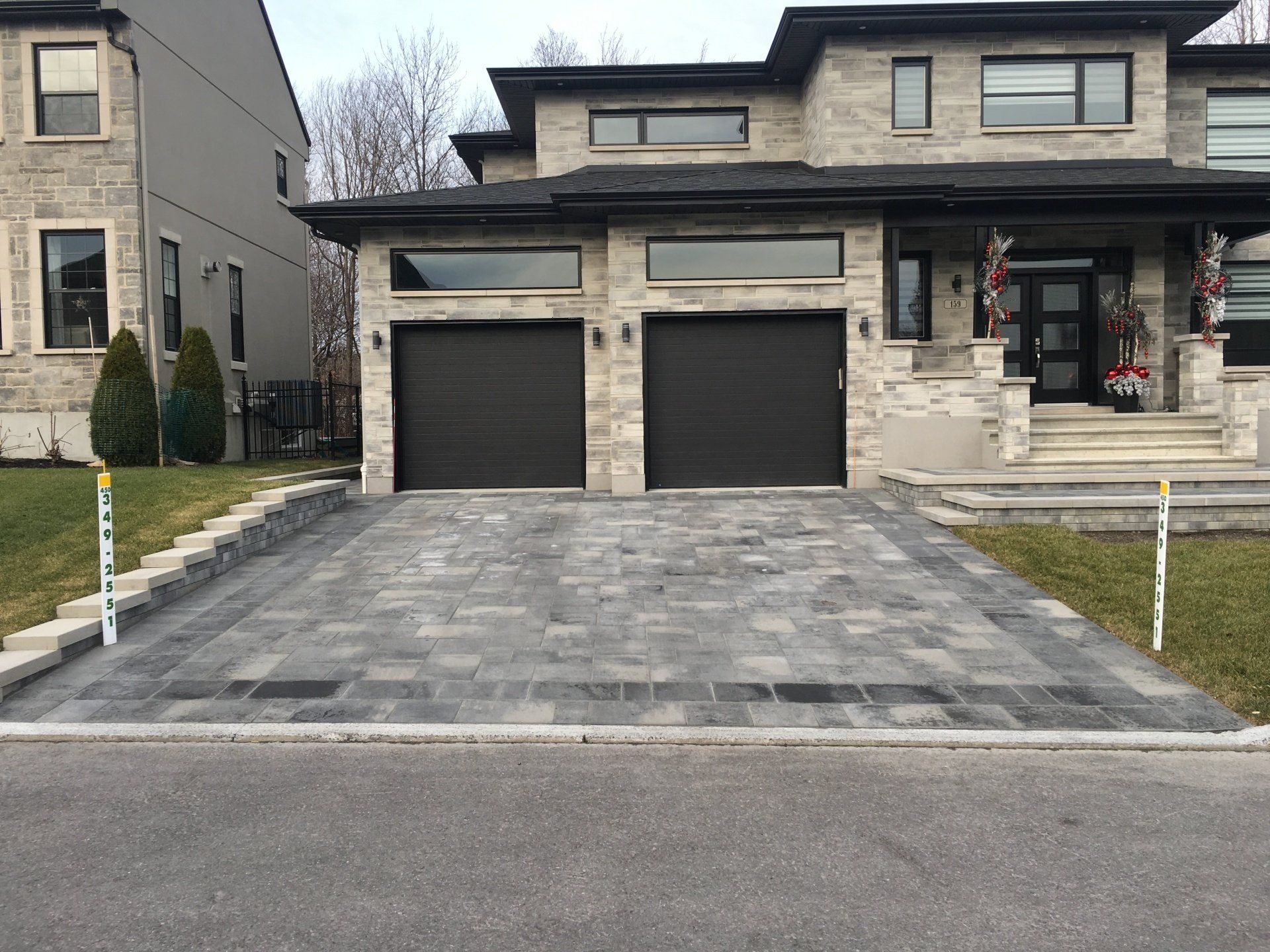 Une grande maison avec deux portes de garage et une allée devant.