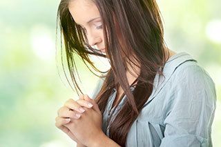 person with long hair prays outdoors