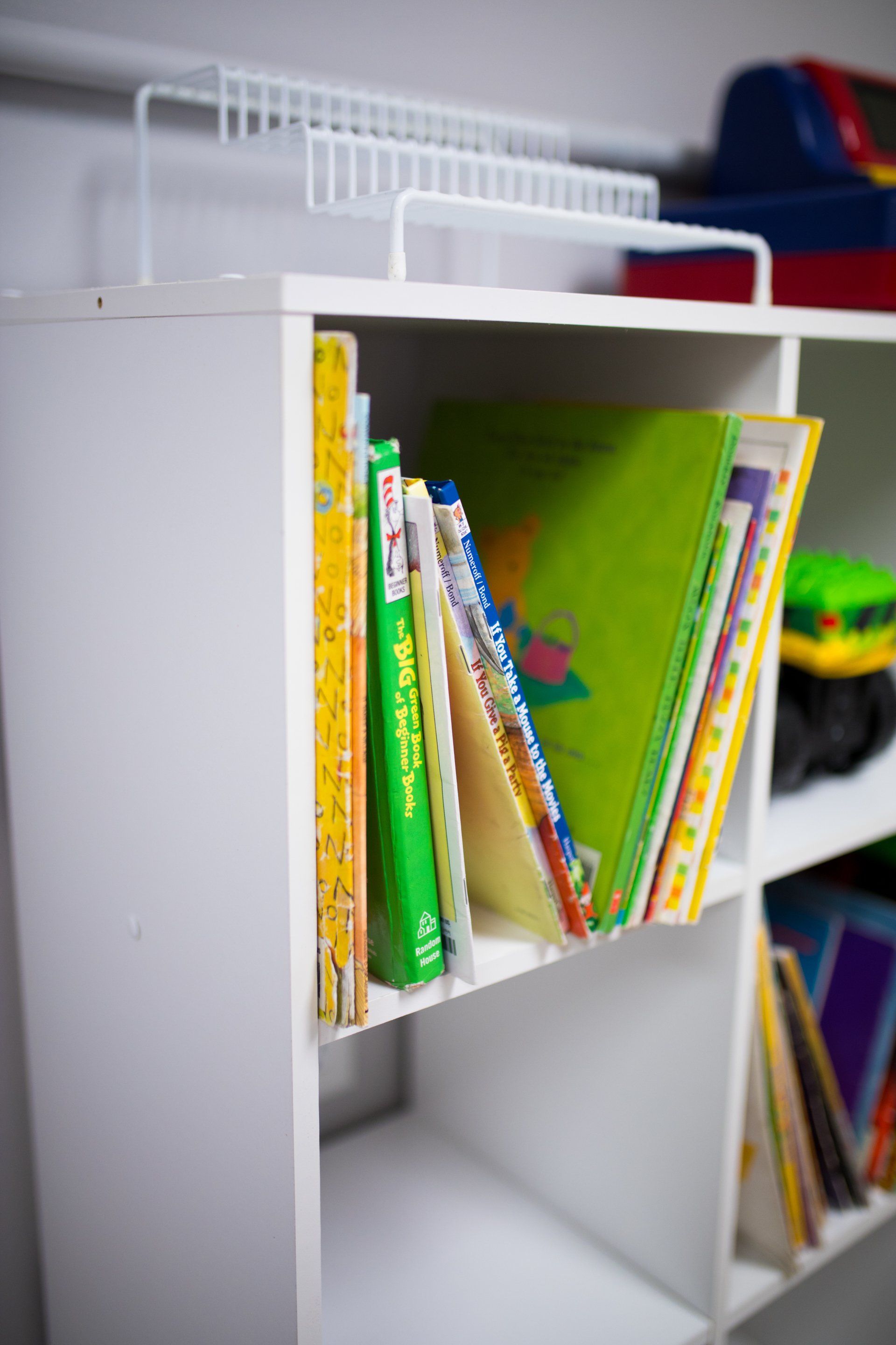 A white shelf filled with books and toys.