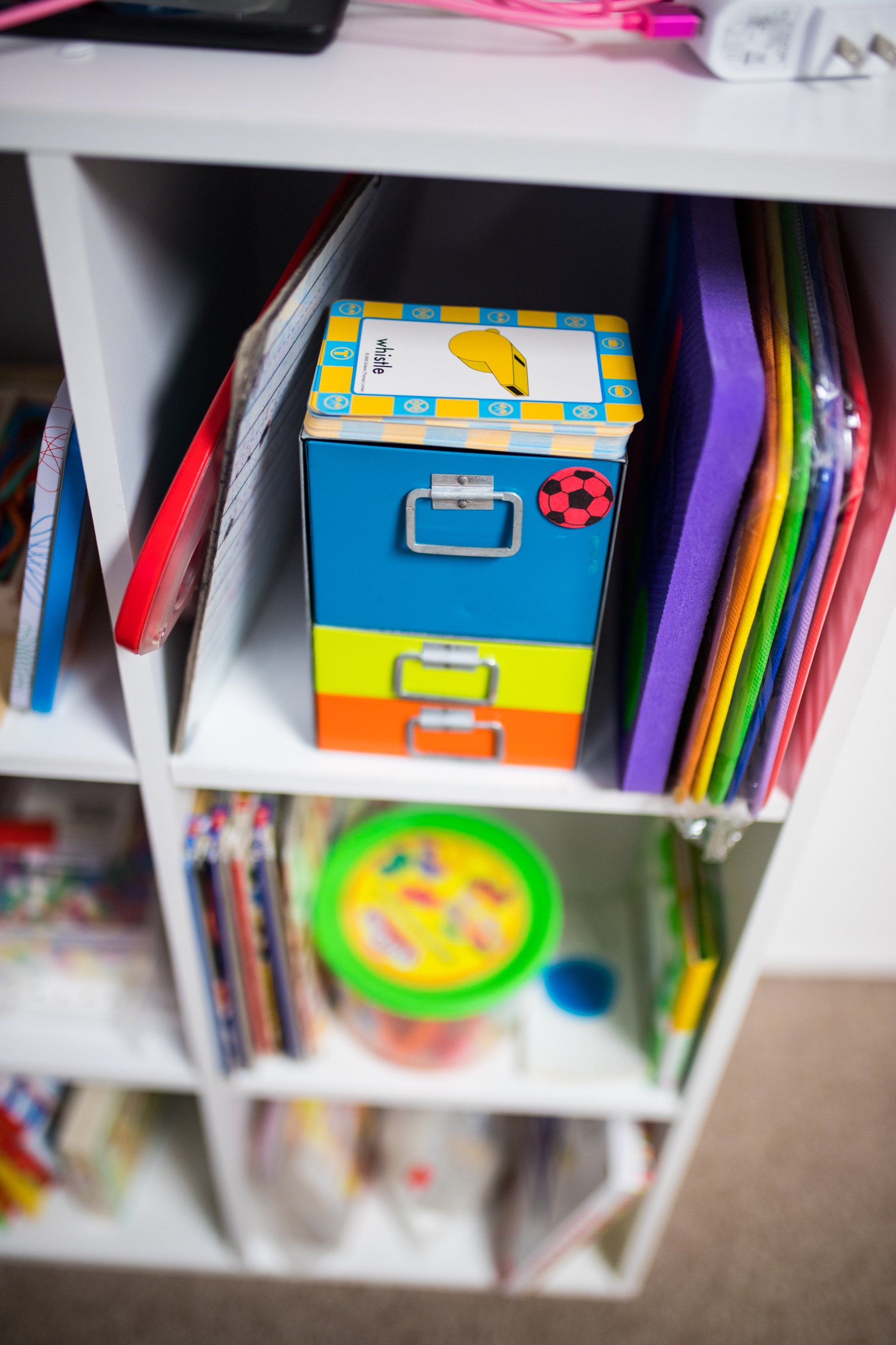 A shelf filled with lots of children 's toys and books.