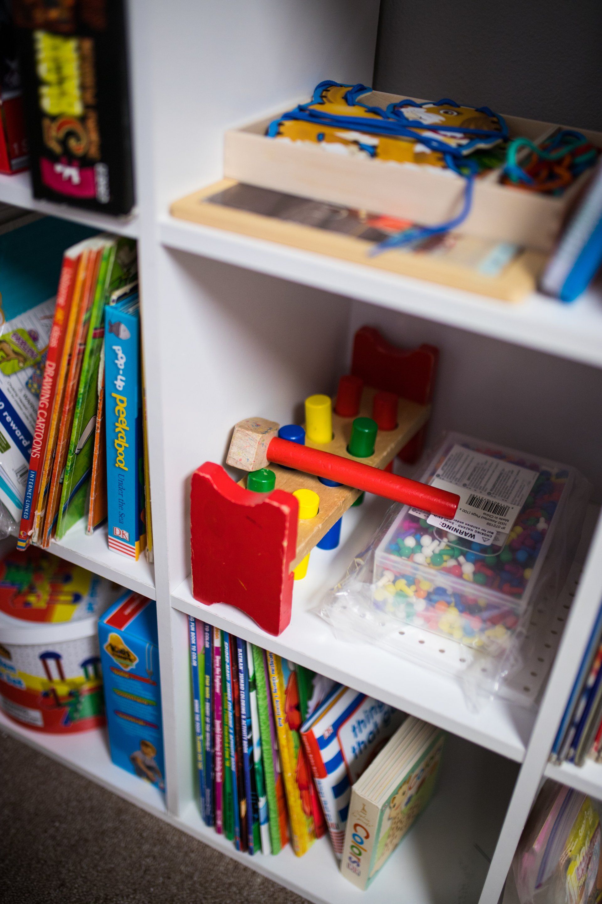 A shelf filled with lots of children 's toys and books.