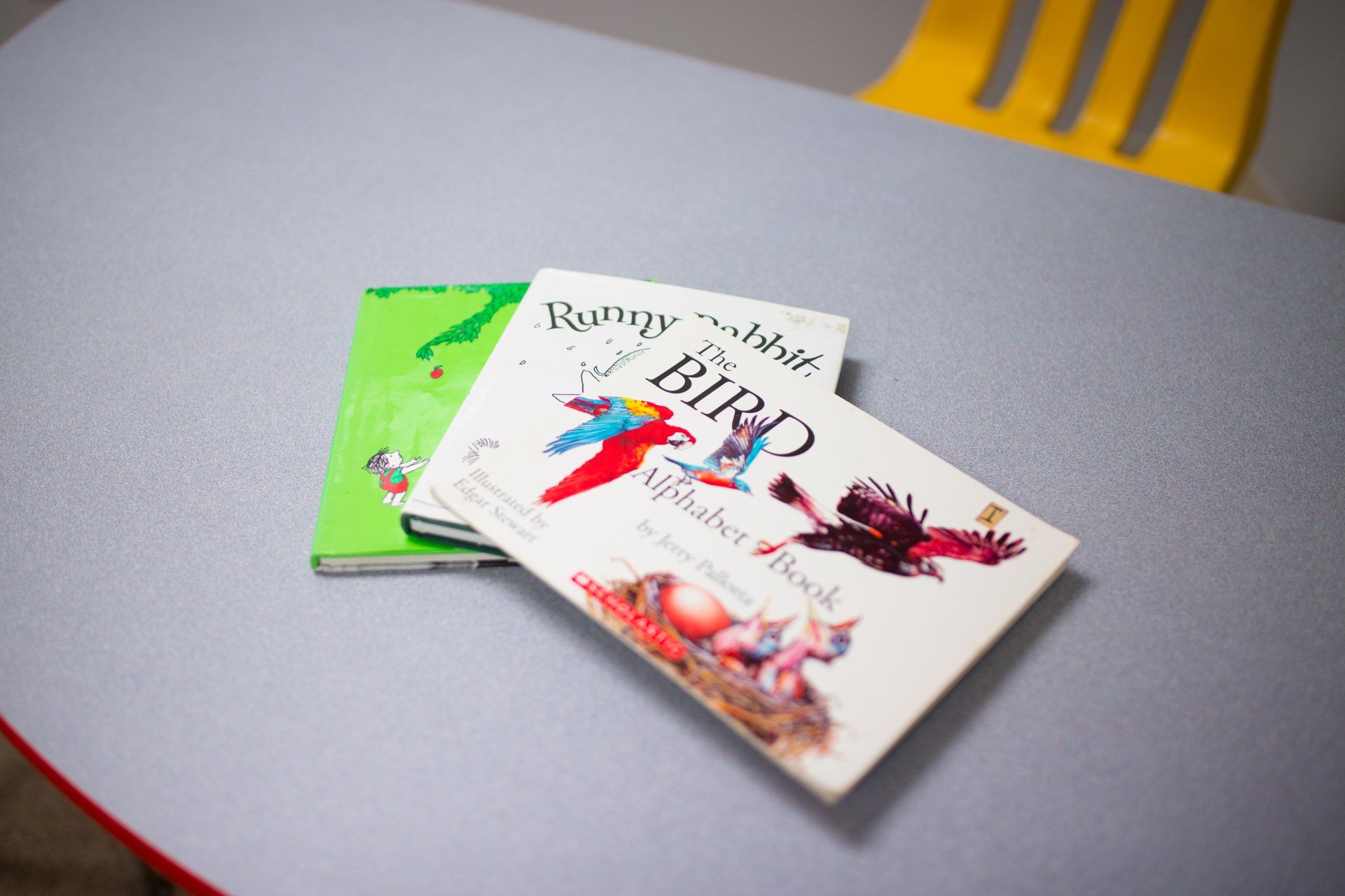 Three children 's books are stacked on top of each other on a table.