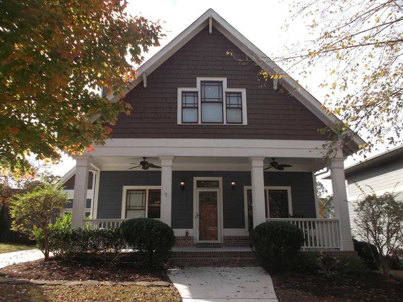 The front of a house with a porch and a tree in front of it