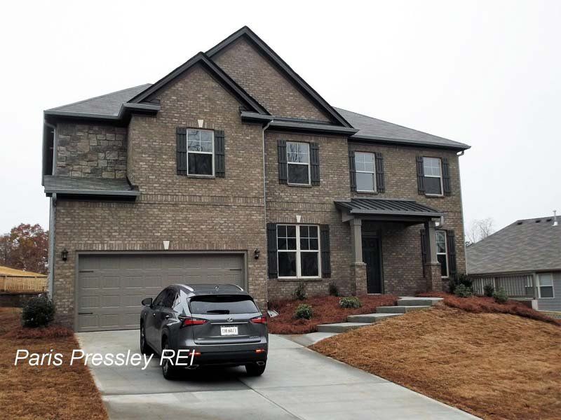 A car is parked in front of a large brick house