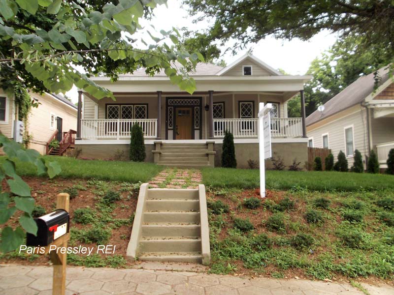 A mailbox in front of a house that is for sale