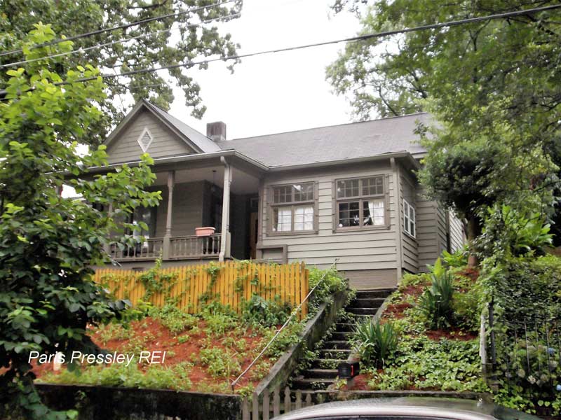 A small house with stairs leading up to it and a car parked in front of it