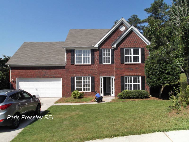 A brick house with a car parked in front of it
