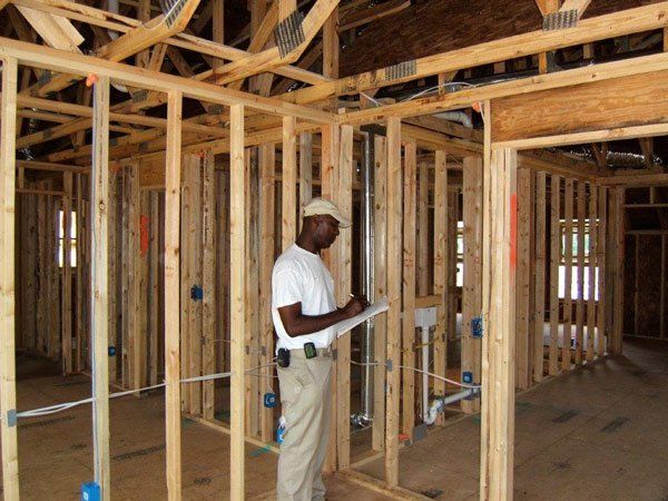 A man is writing on a clipboard in a house under construction