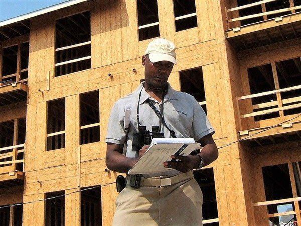 A man standing in front of a building holding a clipboard