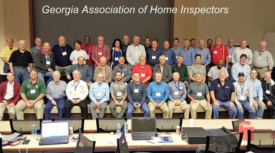 A group of people are posing for a picture in front of a sign that says georgia association of home inspectors