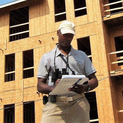 A man standing in front of a building holding a clipboard and binoculars