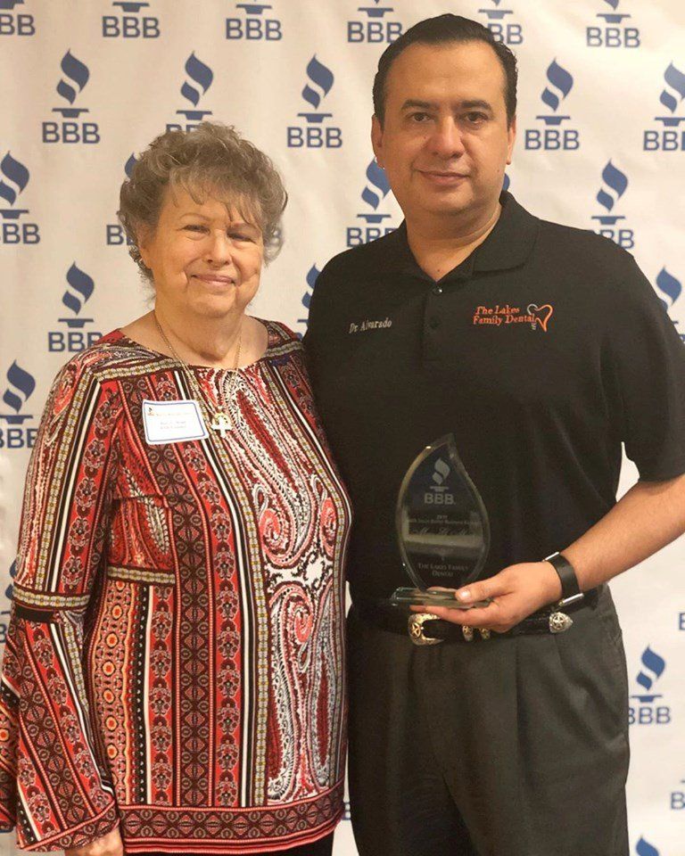 A man and woman are posing for a picture in front of a bbb backdrop