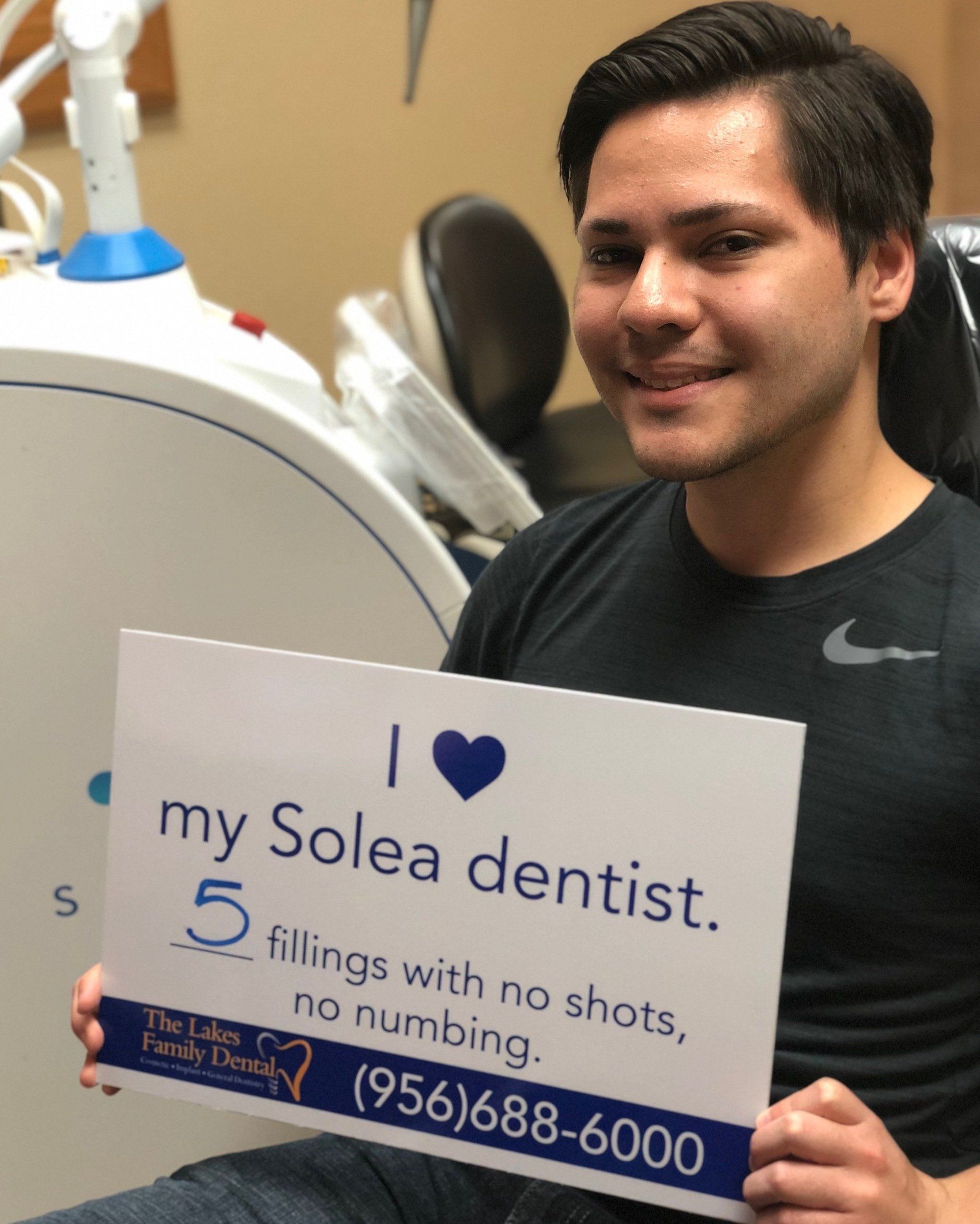 A man holding a sign that says i love my solea dentist