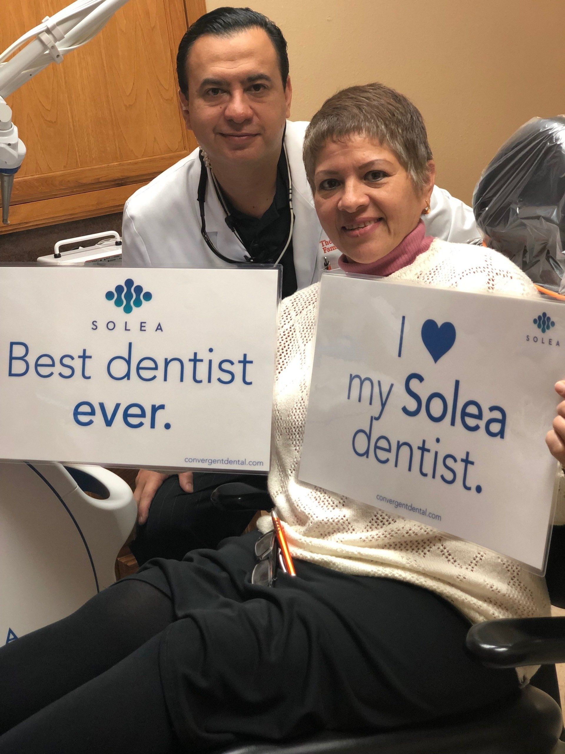 A woman in a dental chair is holding a sign that says i love my solea dentist