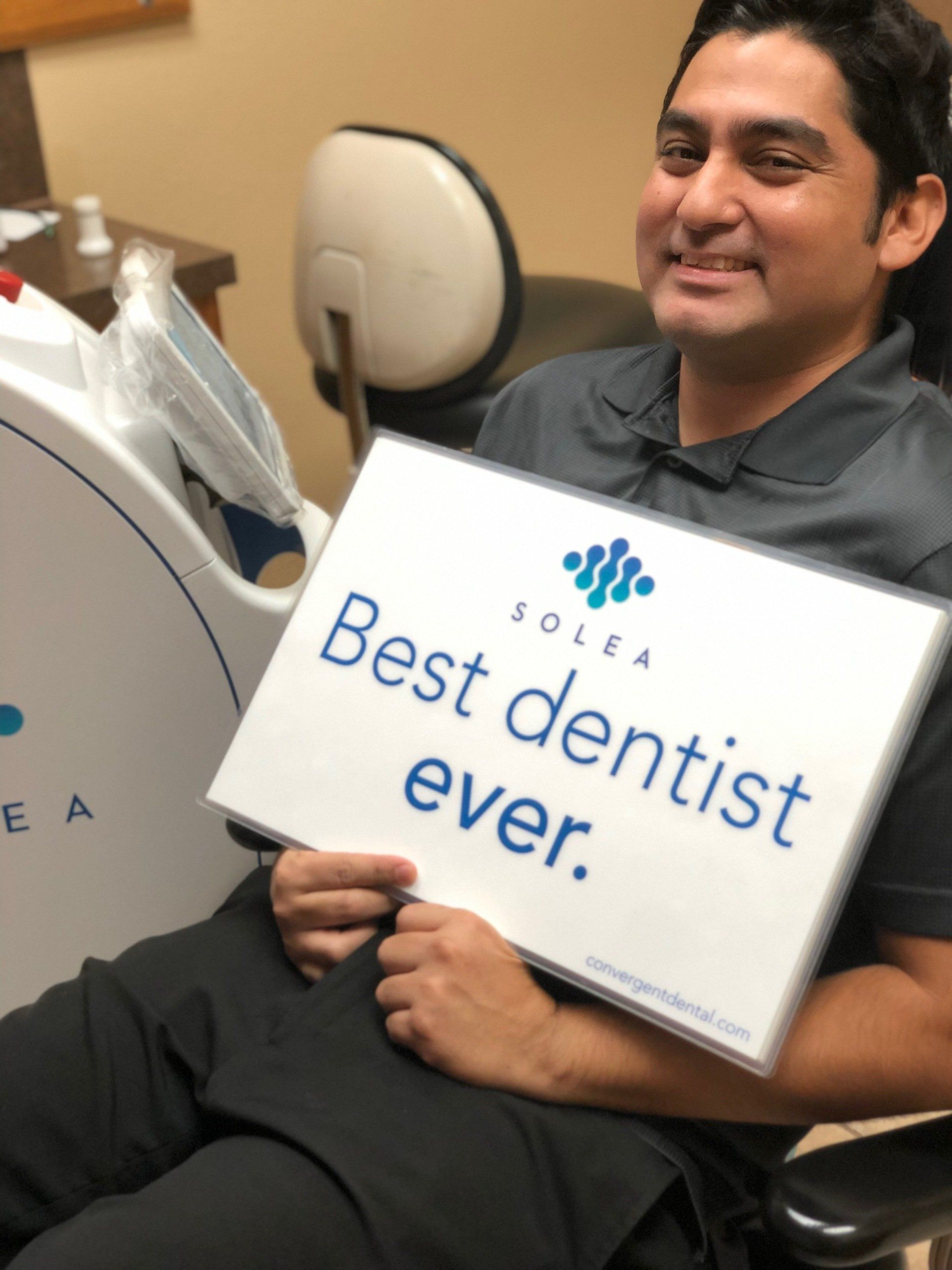 A man holding a sign that says best dentist ever