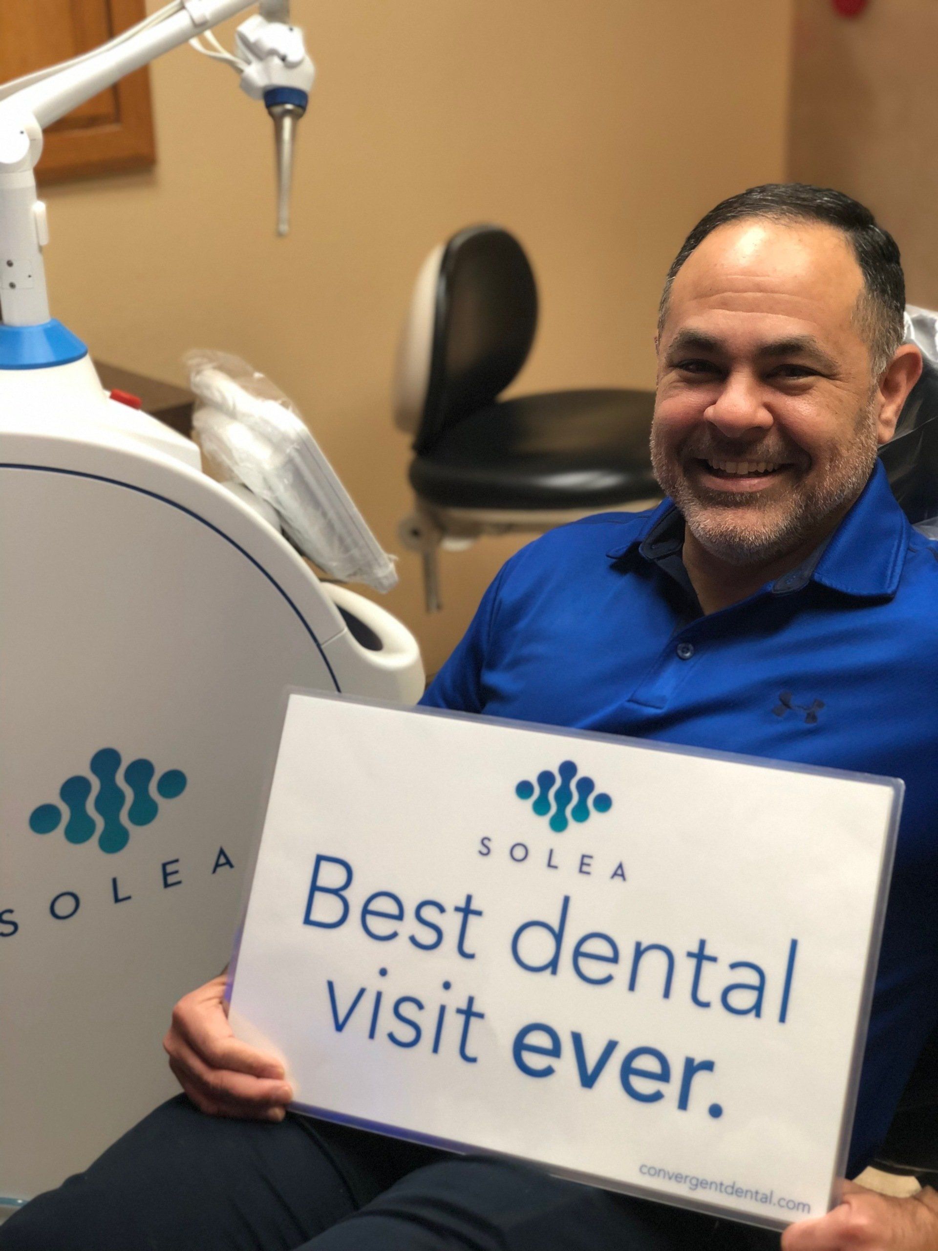 A man holding a sign that says best dental visit ever
