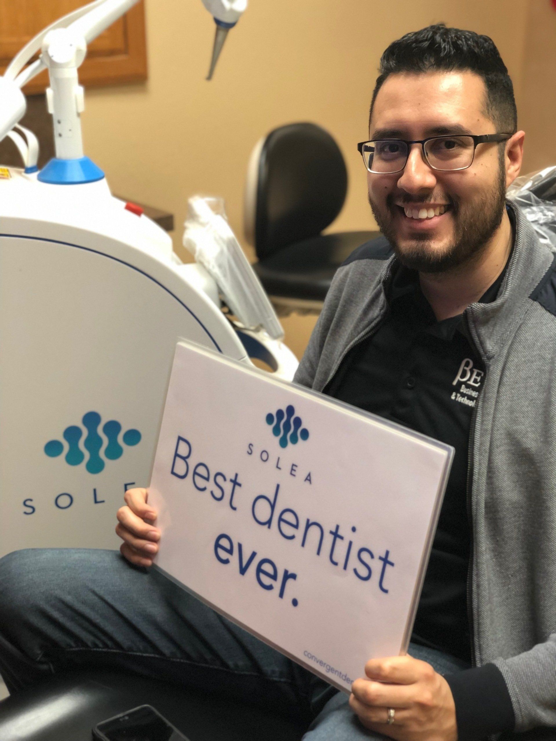 A man holding a sign that says best dentist ever