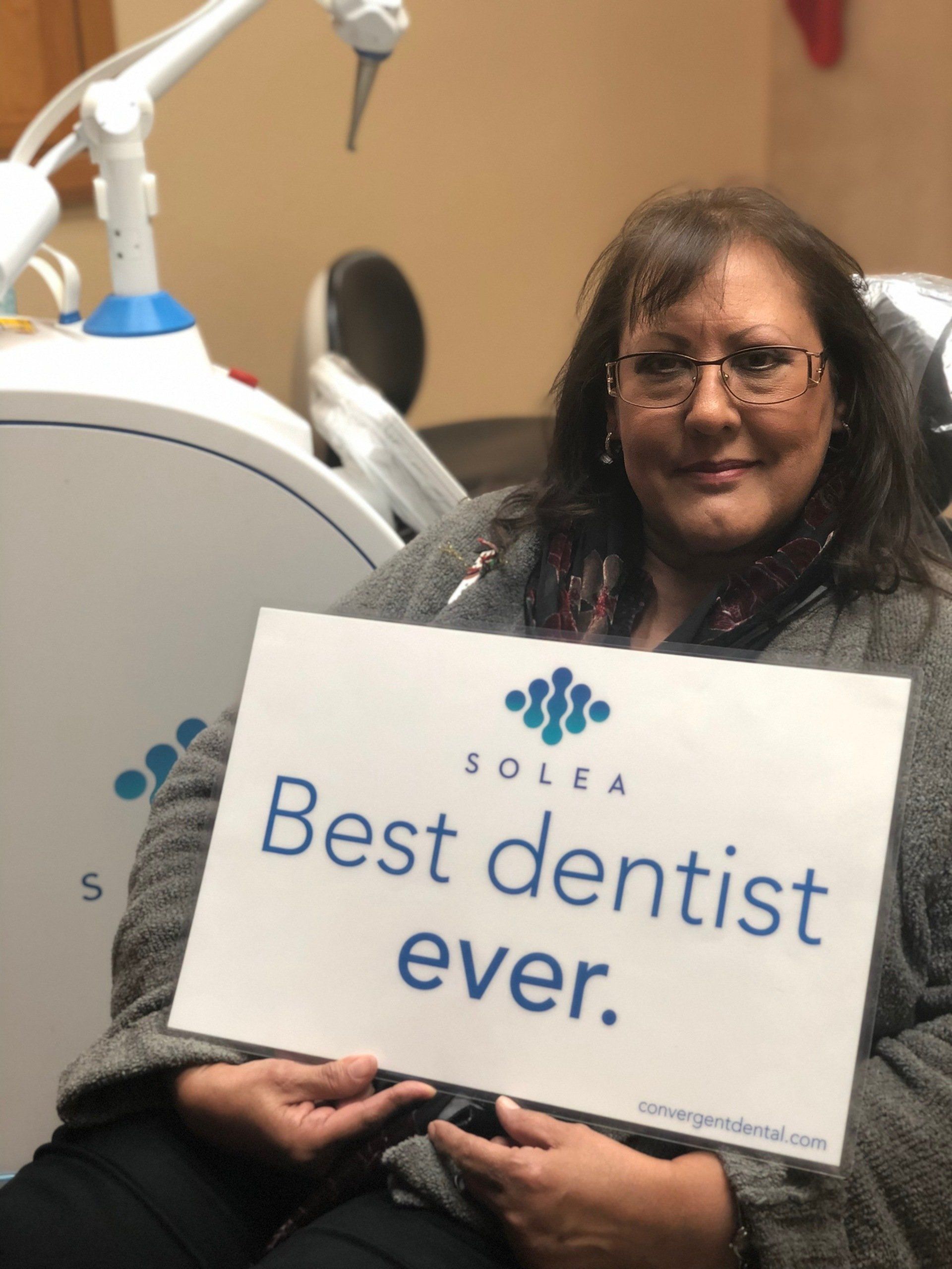 A woman holding a sign that says best dentist ever