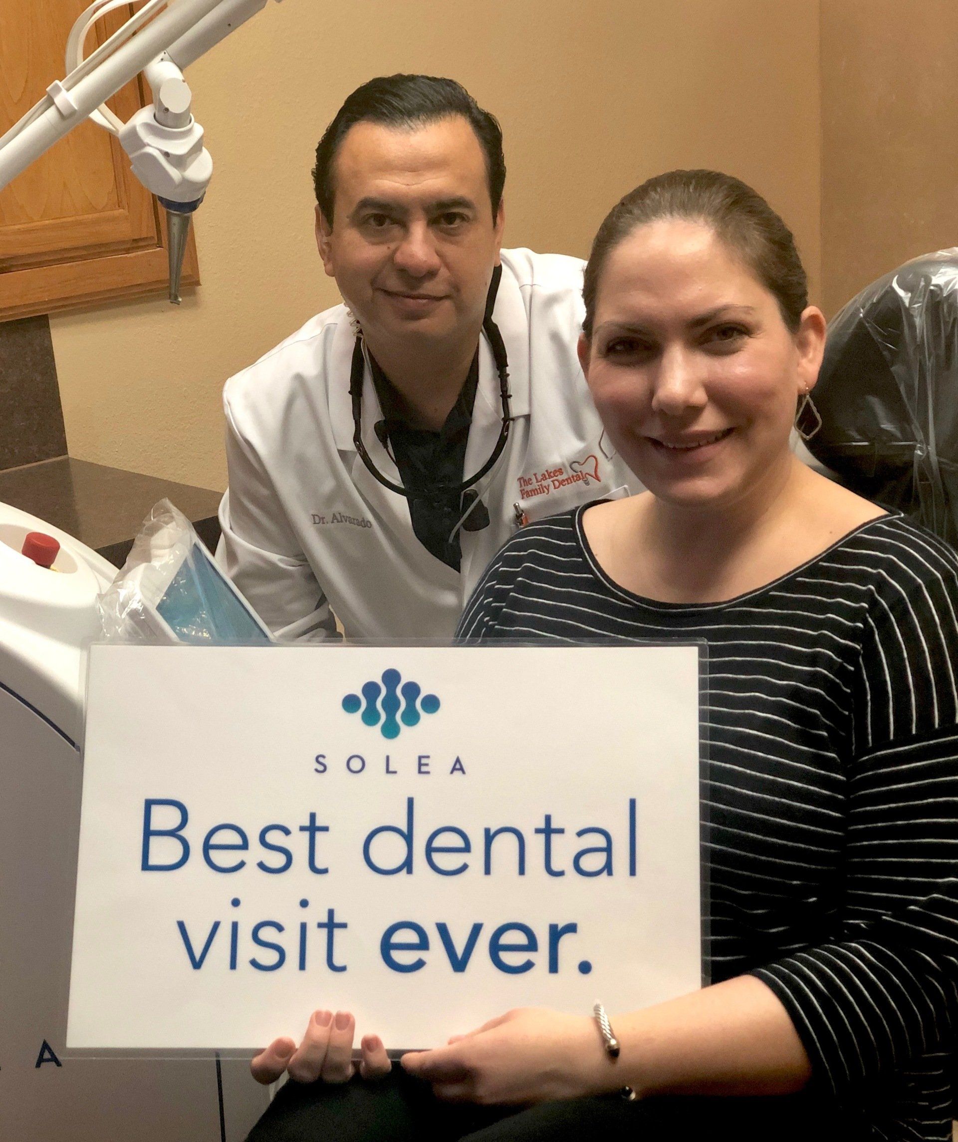 A woman holding a sign that says best dental visit ever