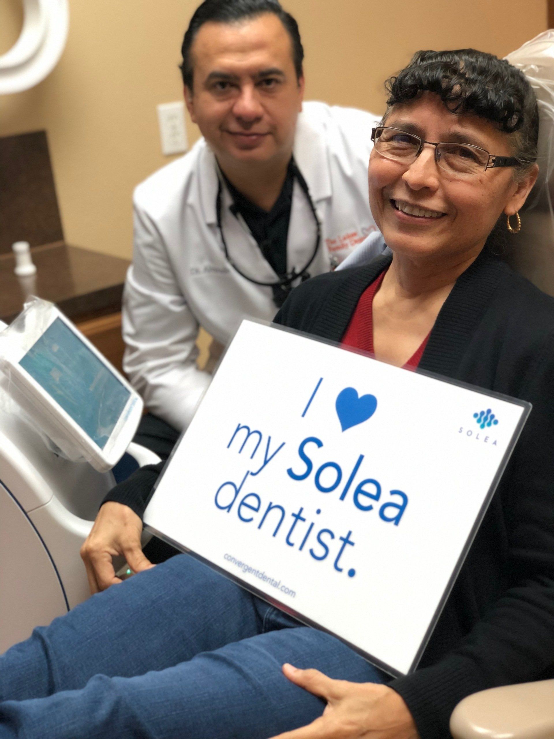 A woman holding a sign that says i love my solea dentist