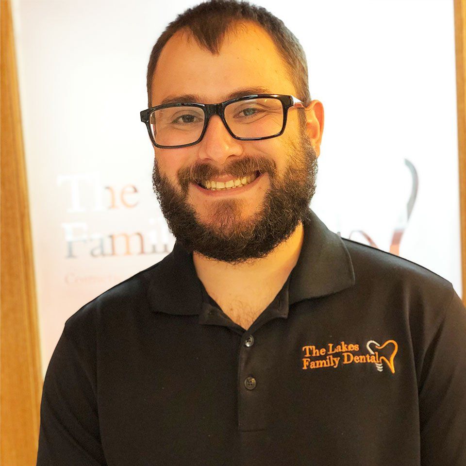 A man wearing glasses and a black shirt that says the lakes family dentistry