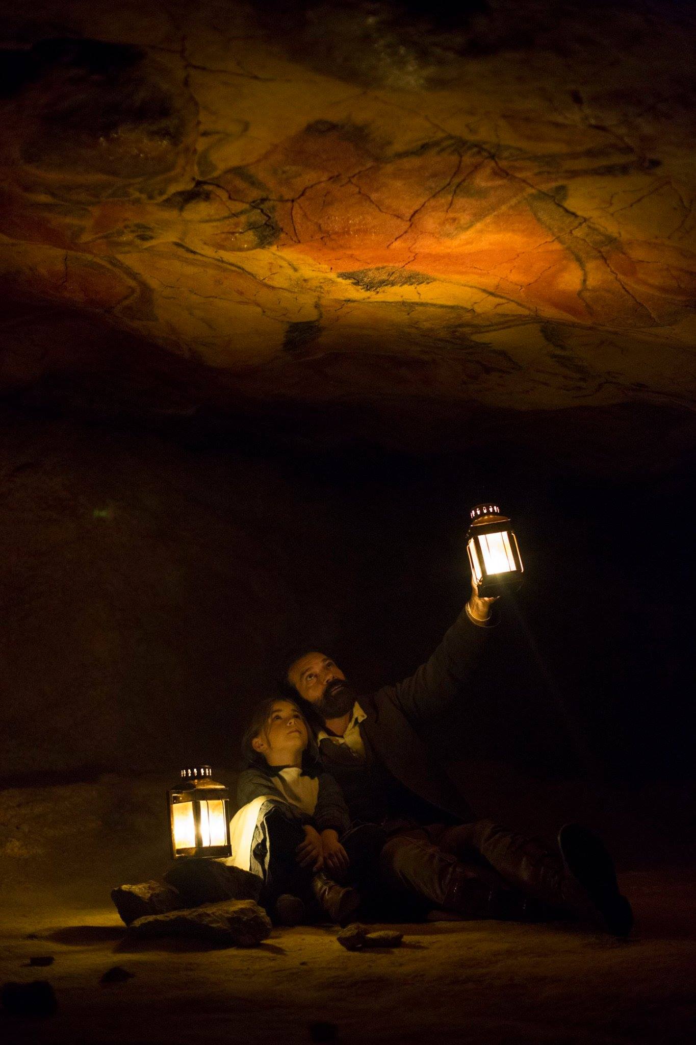 Un grupo de personas sostiene linternas en una cueva oscura.