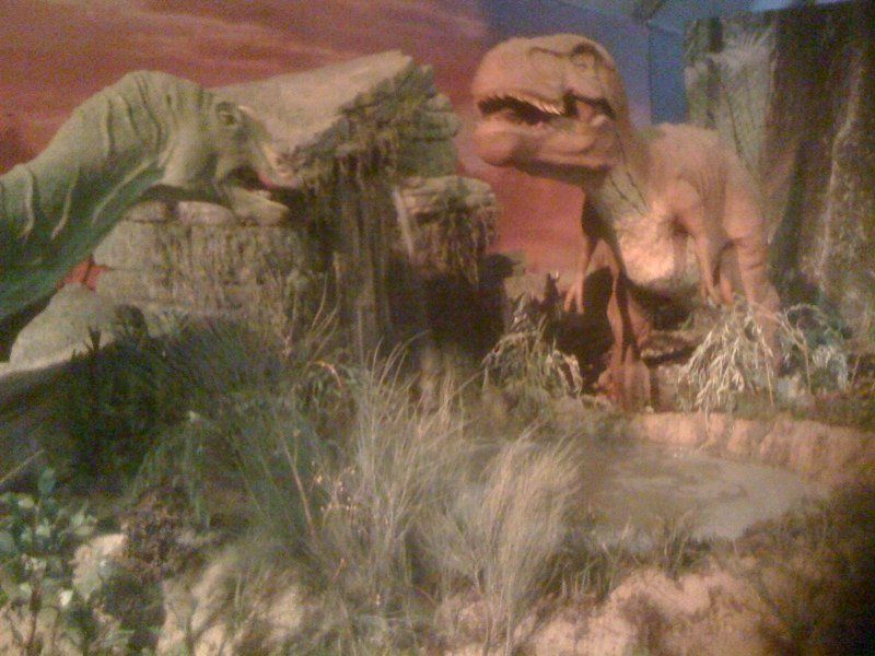 Un grupo de dinosaurios está parado en un campo.