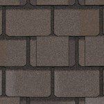 Close-up of brown asphalt roof shingles with a rectangular pattern.
