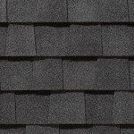 Close-up of overlapping dark gray asphalt roof shingles.