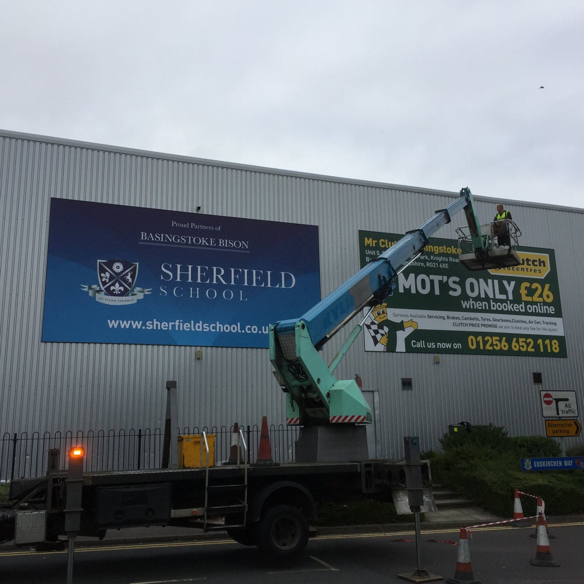 Cherry picker installing advertising signs on side of building