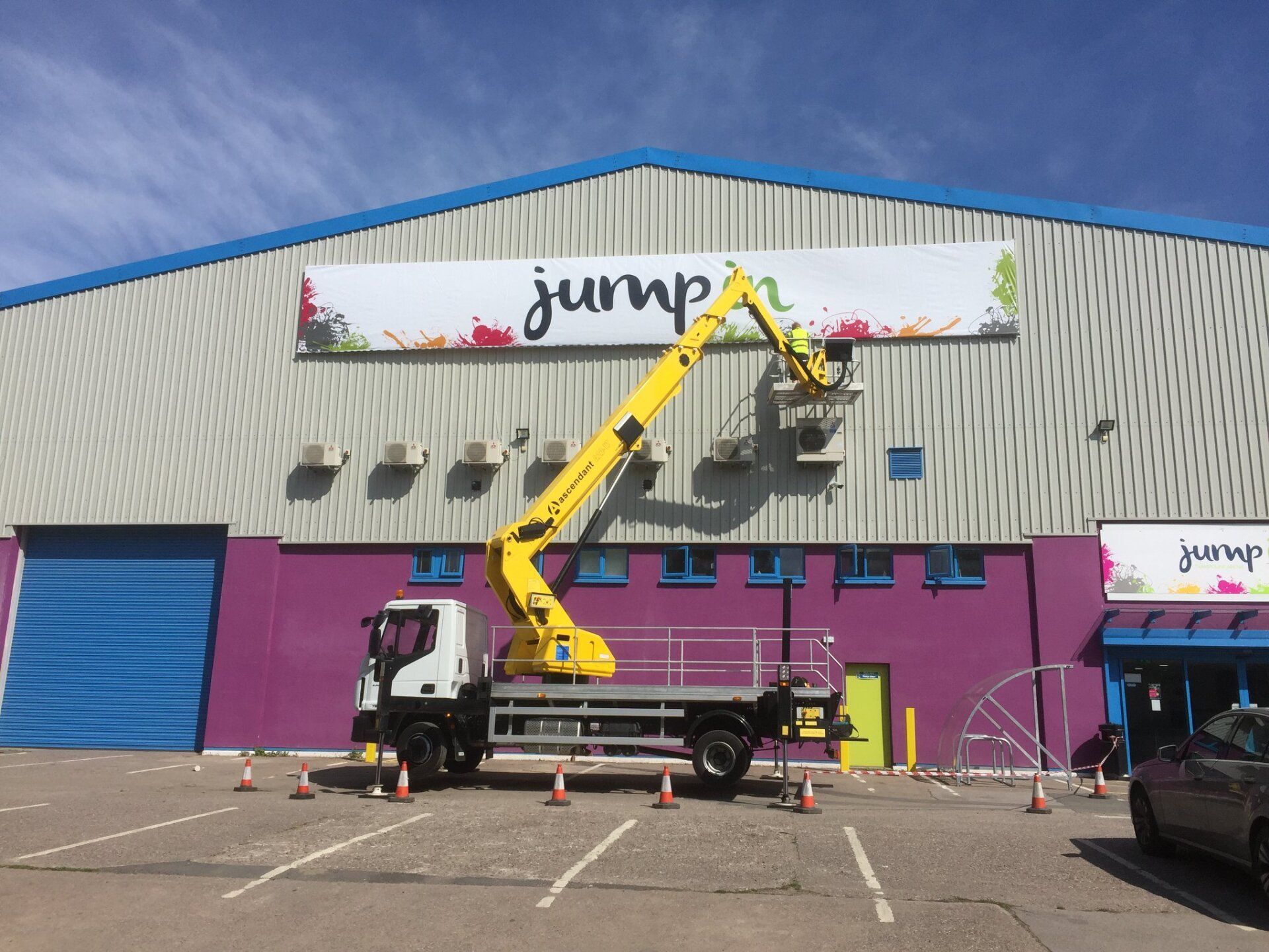 Cherry picker installing sign on industrial building