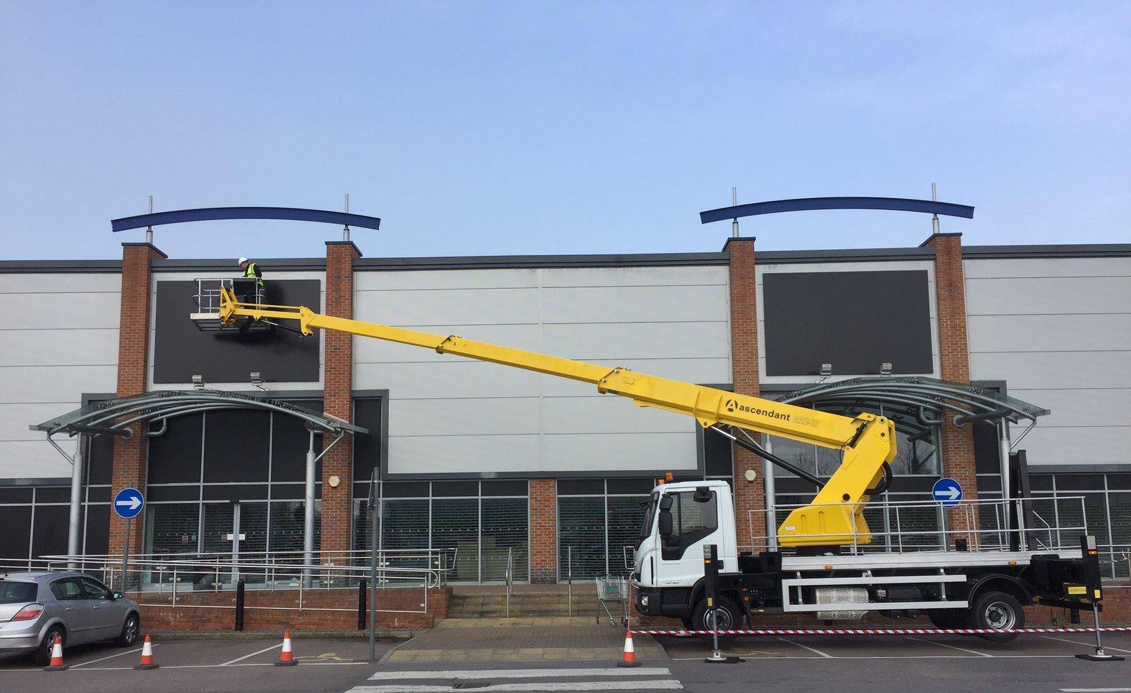Cherry picker accessing front of retail shop