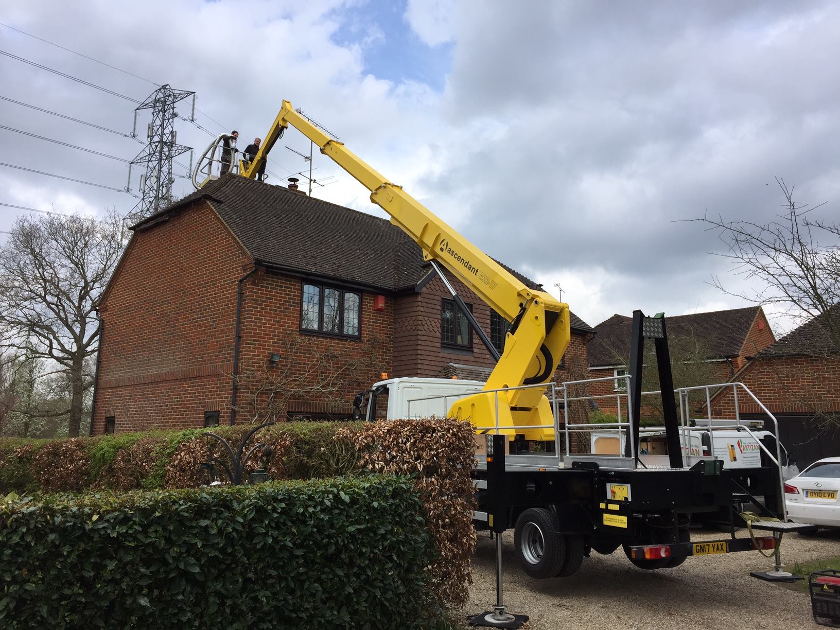 Cherry picker and operatives working on roof of house