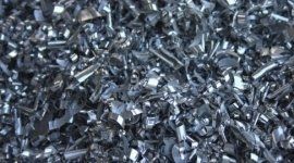 Un mucchio di pezzi di scarto metallici lucidi, argentati e grigi, che riempiono la cornice.