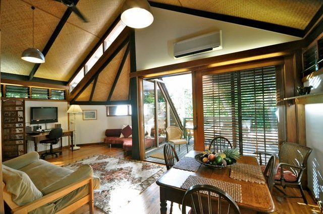 Spacious wood-paneled living room with dining table, sofa, and large windows with blinds