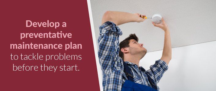 Man Installing Smoke Detector on Ceiling