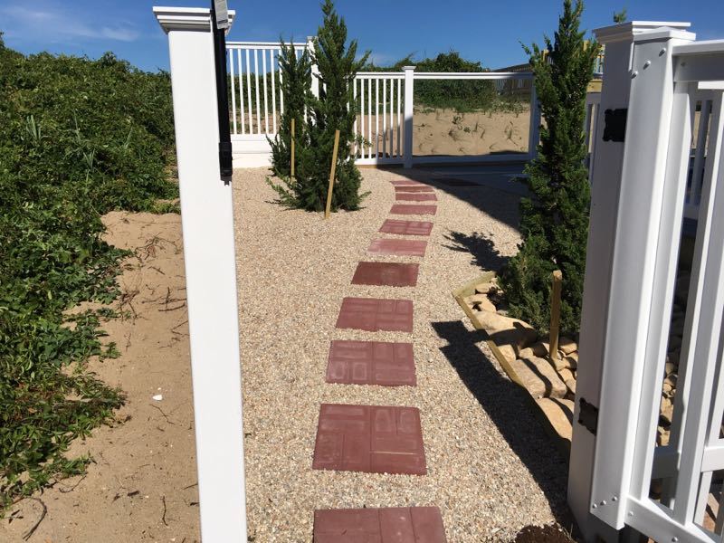 Red Concrete paver pathway embedded in pea rock lawn.