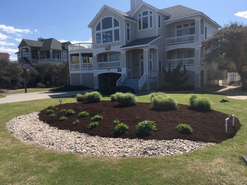 Flowers and bushes in a mulched bed.