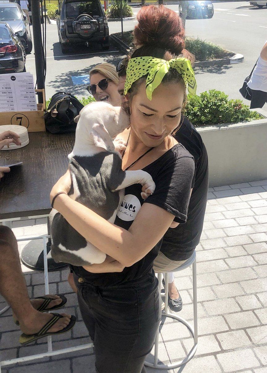 A woman is holding a small dog in her arms.