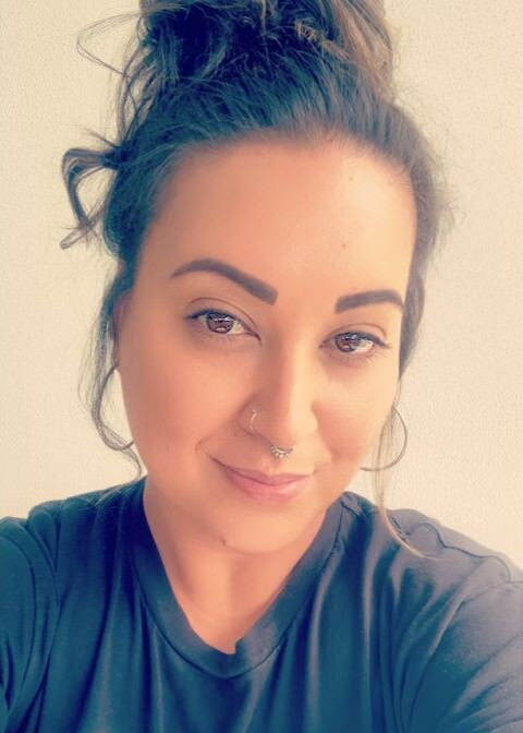 A woman is taking a selfie with her hair in a bun.