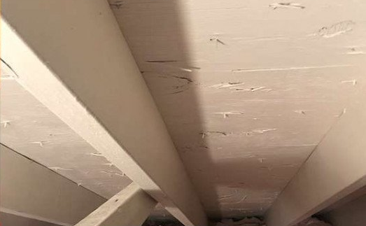 A close up of a ceiling in a room with a staircase.