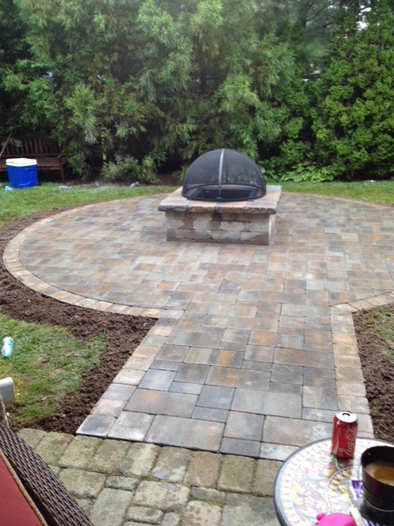 square bricked fireplace with a stone patio in the backyard